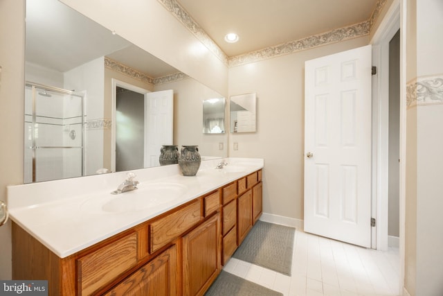 full bath featuring double vanity, baseboards, a sink, and a stall shower