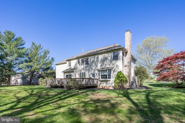 back of house with a lawn, a chimney, and a deck