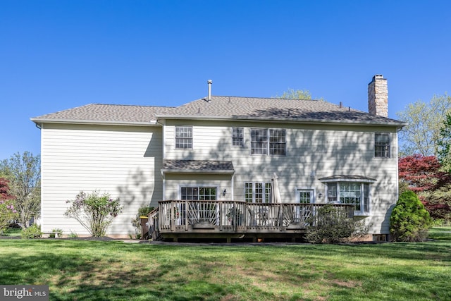 rear view of property with a lawn, a chimney, and a deck