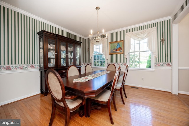 dining area featuring ornamental molding, light wood-type flooring, wallpapered walls, and a chandelier