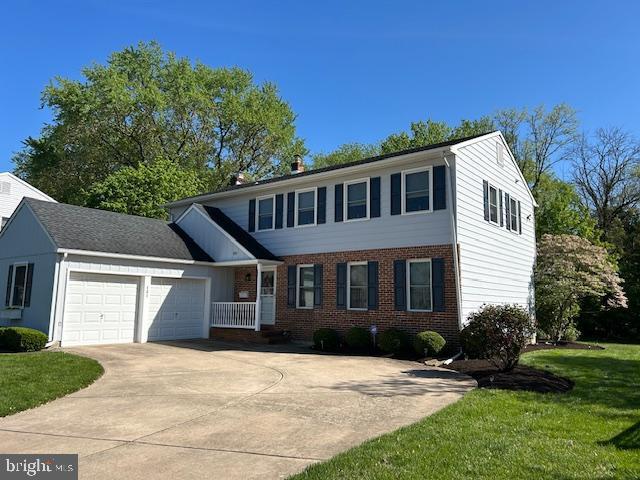 view of front of house featuring brick siding, an attached garage, driveway, and a front yard