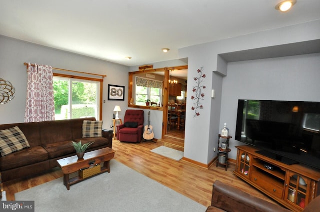 living area with baseboards, a chandelier, and wood finished floors