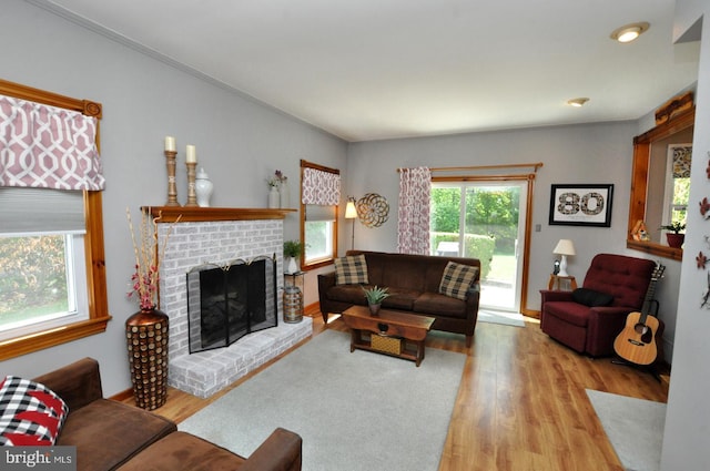 living room with baseboards, a brick fireplace, and wood finished floors