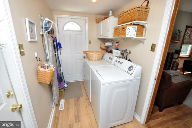 laundry area featuring light wood finished floors, cabinet space, and washer and dryer