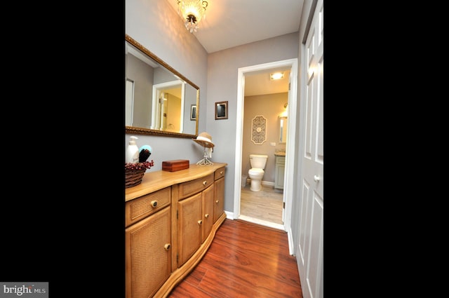 bathroom with toilet, baseboards, wood finished floors, and vanity