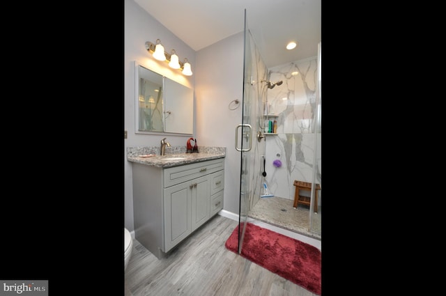 bathroom featuring a marble finish shower, baseboards, vanity, and wood finished floors