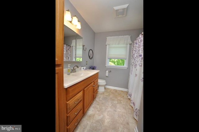 bathroom with vanity, baseboards, toilet, and visible vents
