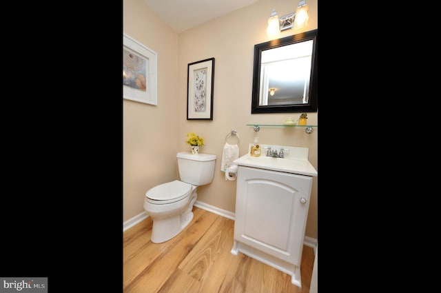 bathroom with vanity, baseboards, wood finished floors, and toilet