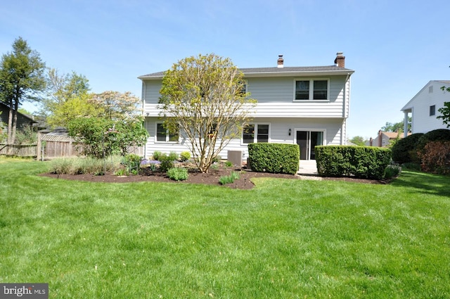 back of house with a lawn, fence, and a chimney
