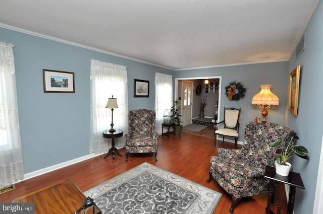 living area with crown molding, baseboards, visible vents, and wood finished floors