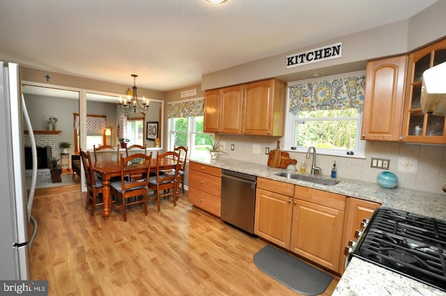 kitchen featuring a sink, appliances with stainless steel finishes, light stone countertops, and a healthy amount of sunlight