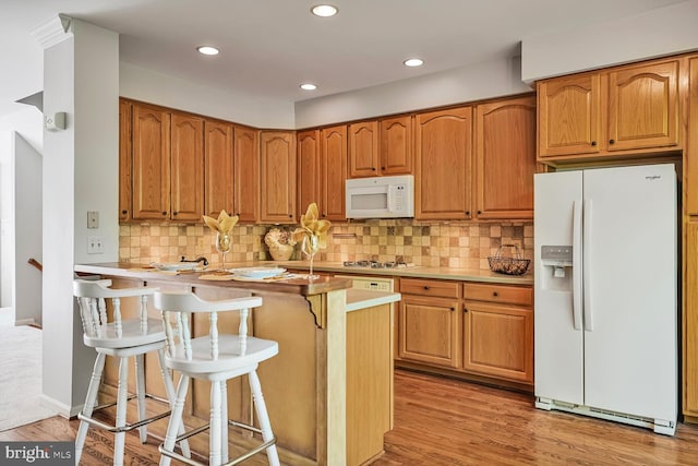 3016 Fallswood Glen Ct, Falls Church, VA 22044 - kitchen featuring decorative backsplash, a kitchen bar, light countertops, light wood-style floors, and white appliances