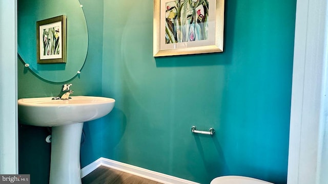 bathroom with baseboards, wood finished floors, and toilet