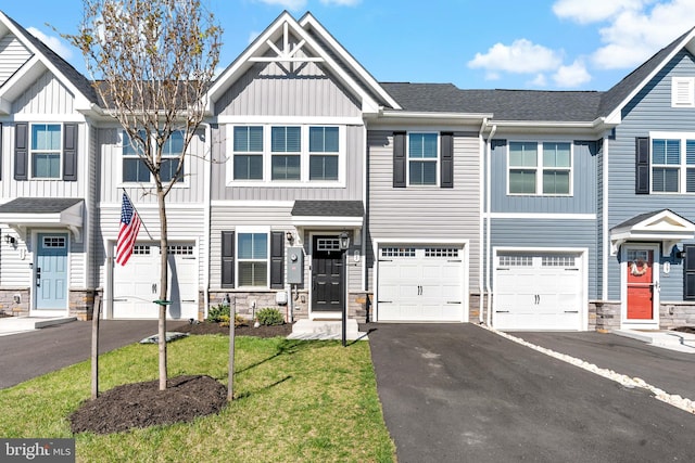 view of property with a garage, board and batten siding, driveway, and stone siding