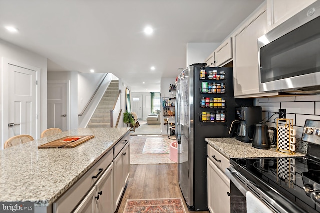 kitchen featuring light stone counters, wood finished floors, a kitchen island, and stainless steel appliances