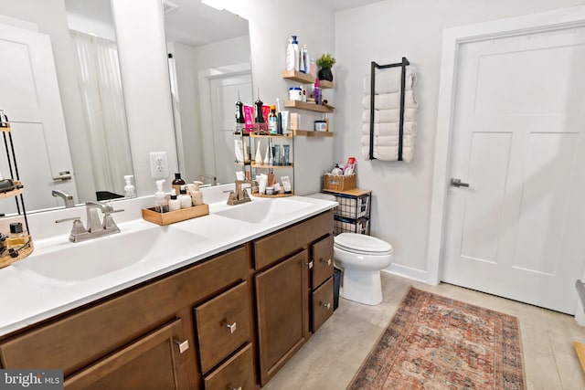 full bathroom with a sink, tile patterned floors, toilet, and double vanity