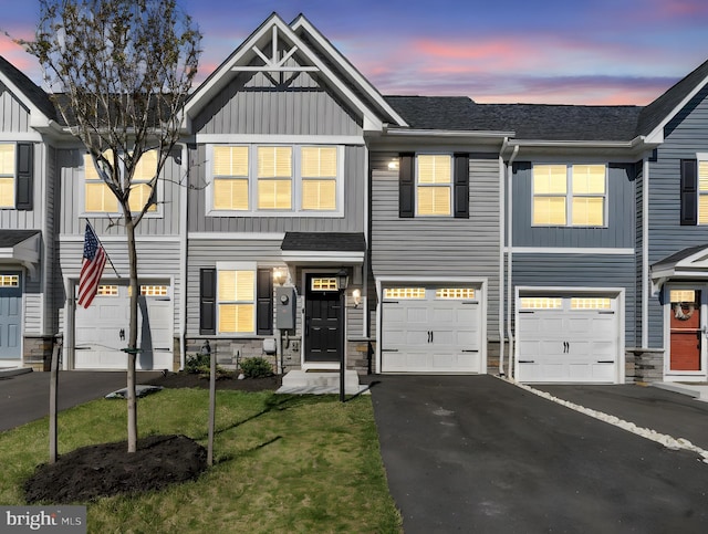 multi unit property featuring a front lawn, stone siding, a garage, board and batten siding, and driveway