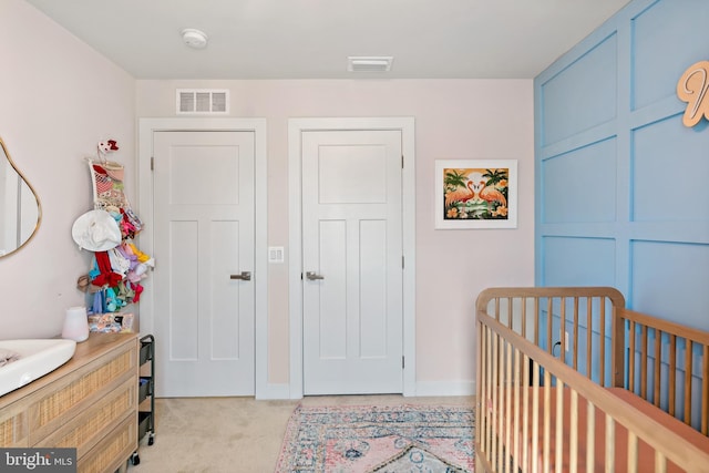 bedroom with a crib, baseboards, light carpet, and visible vents