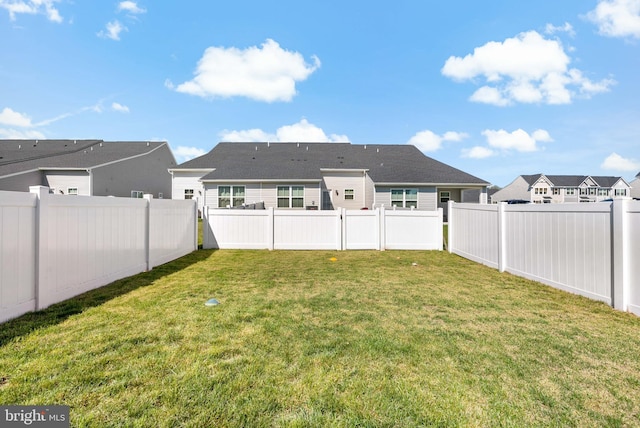 rear view of house with a residential view, a yard, and a fenced backyard