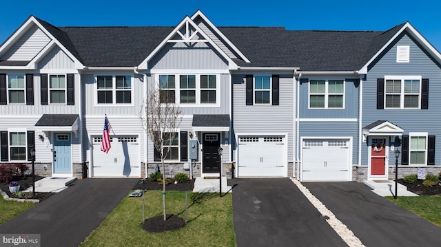 view of property with a garage, board and batten siding, driveway, and stone siding