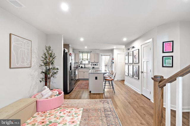 kitchen with a kitchen island, a kitchen bar, light wood-type flooring, recessed lighting, and appliances with stainless steel finishes