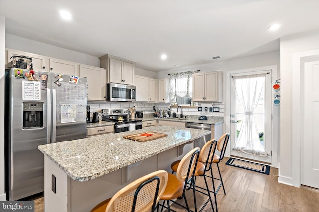 kitchen featuring a breakfast bar area, visible vents, appliances with stainless steel finishes, a center island, and light wood-type flooring