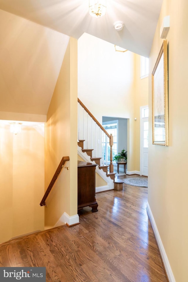 foyer with baseboards, stairs, wood finished floors, and a towering ceiling