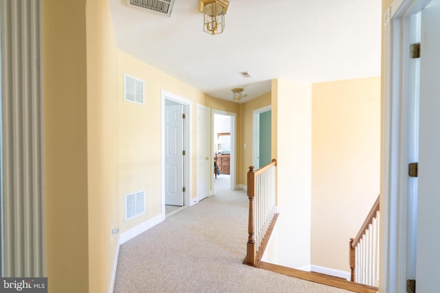 corridor featuring visible vents, carpet flooring, and an upstairs landing