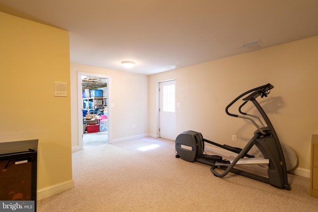 exercise area featuring baseboards and light colored carpet