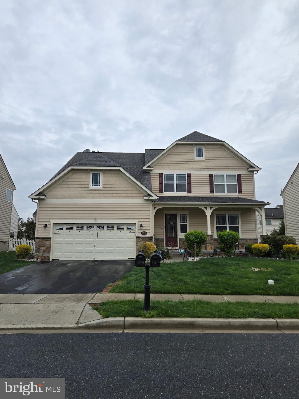 view of front of property with a front yard, driveway, stone siding, and a garage