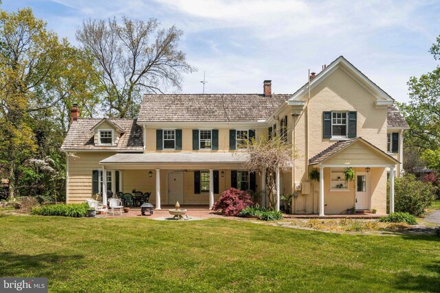 back of house featuring a yard and a chimney