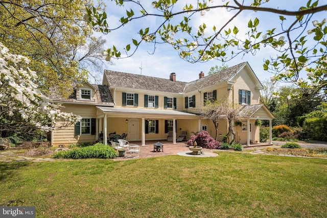 back of property with a lawn, a chimney, and a patio