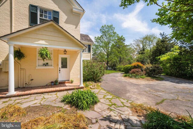 entrance to property featuring covered porch and brick siding