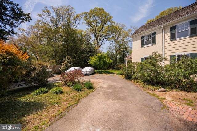 view of yard featuring fence and aphalt driveway