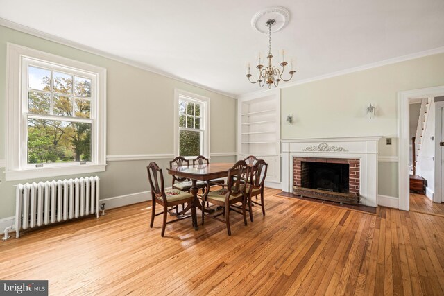 dining space with crown molding, radiator, built in features, and hardwood / wood-style floors