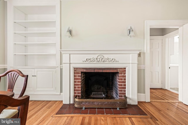 living room with built in features, a fireplace, and hardwood / wood-style flooring