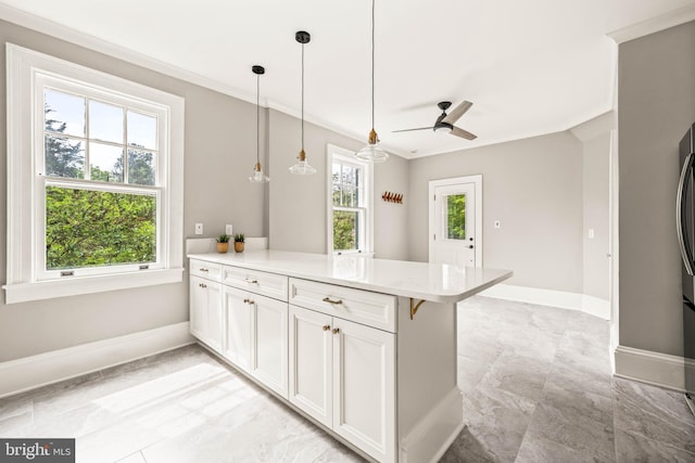 kitchen with ceiling fan, baseboards, a peninsula, ornamental molding, and white cabinetry