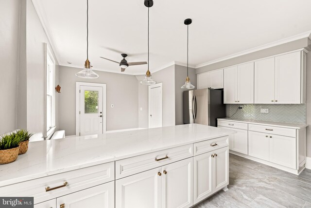 kitchen with white cabinets, light stone counters, freestanding refrigerator, tasteful backsplash, and ornamental molding
