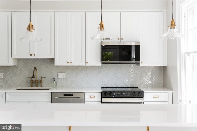 kitchen featuring white cabinets, a sink, light countertops, stainless steel appliances, and decorative backsplash