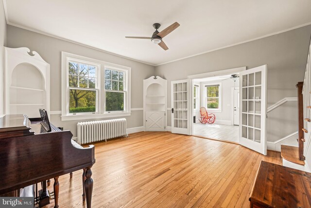 interior space with radiator heating unit, stairway, french doors, a ceiling fan, and light wood-style flooring