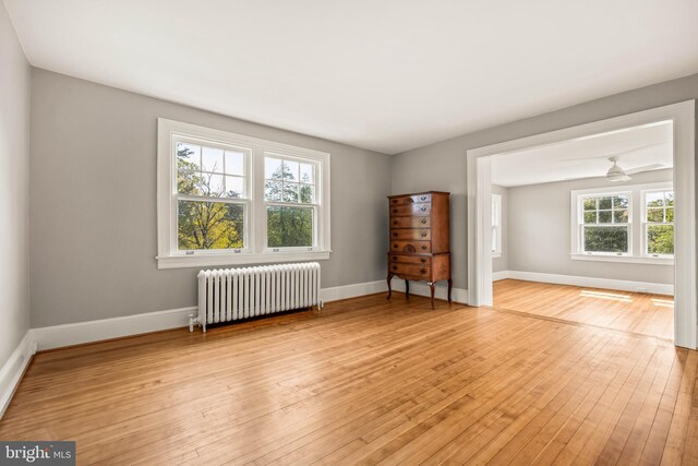 spare room with light wood-style floors, radiator, and baseboards