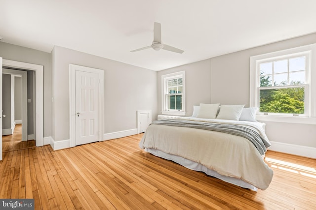 bedroom with baseboards, multiple windows, and light wood-style floors