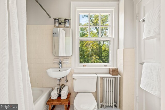 full bathroom featuring a sink, toilet, shower / bathtub combination with curtain, radiator heating unit, and tile walls