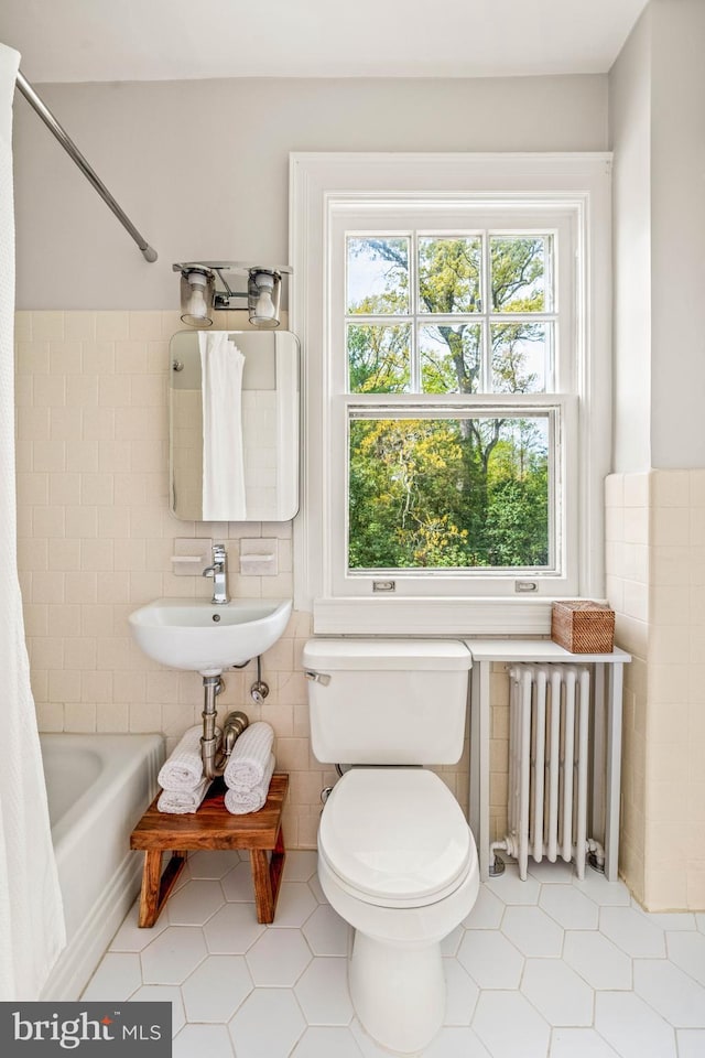 bathroom with toilet, tile patterned floors, tile walls, and radiator