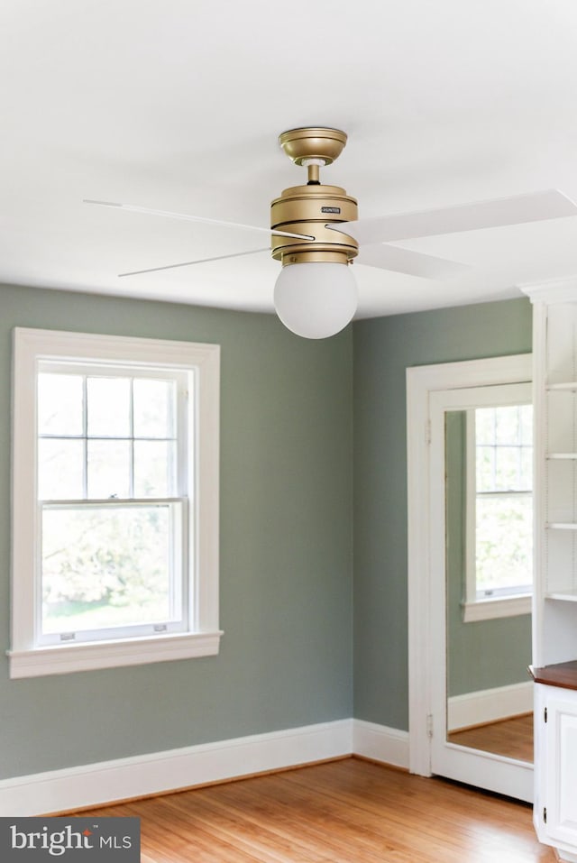 empty room with a ceiling fan, baseboards, and light wood-style floors