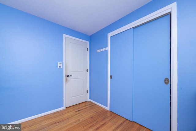 unfurnished bedroom featuring wood finished floors, baseboards, and a closet