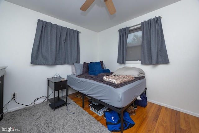 bedroom featuring baseboards, wood finished floors, and ceiling fan