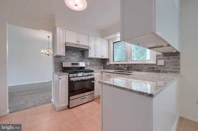 kitchen with stainless steel gas range, white cabinetry, under cabinet range hood, light stone counters, and a sink