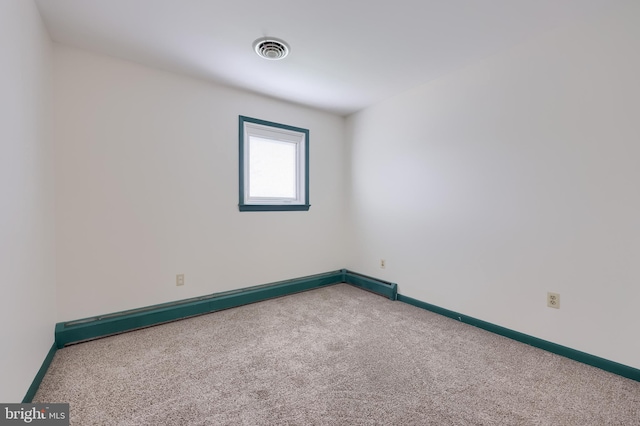 unfurnished room featuring visible vents, a baseboard heating unit, carpet, and baseboards