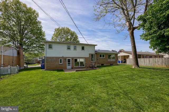 rear view of house with a lawn, brick siding, and fence